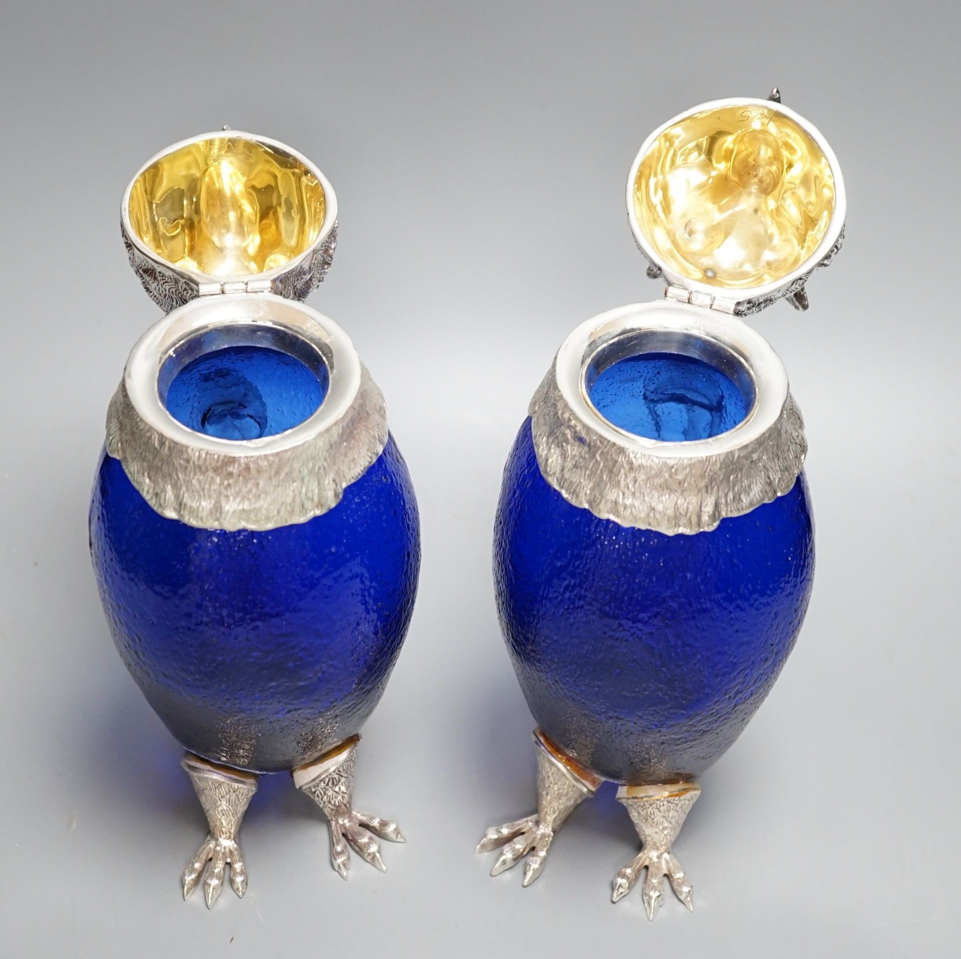 A pair of modern silver plated and blue glass novelty owl flasks, 28.5 cms high.